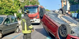 Perde il controllo dell’auto e si ribalta dopo l’urto con le auto in sosta