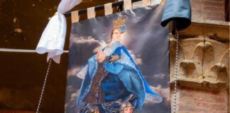 Palio di Siena 16 agosto, il Drappellone fa discutere: polemiche sul volto della Madonna ‘androgina’